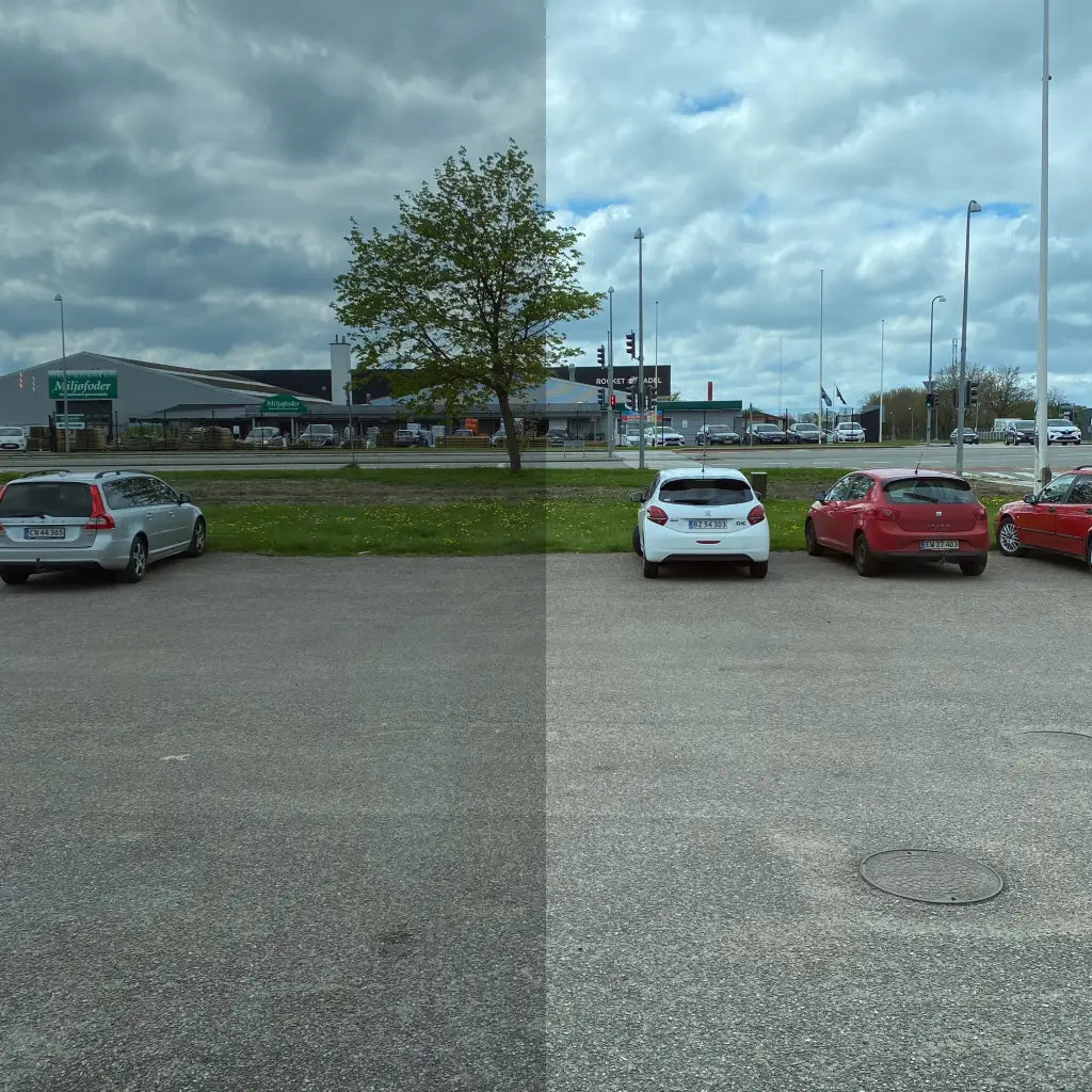 En parkeringsplads med biler, opdelt i to. Venstre side er mørkere, højre side er lysere.