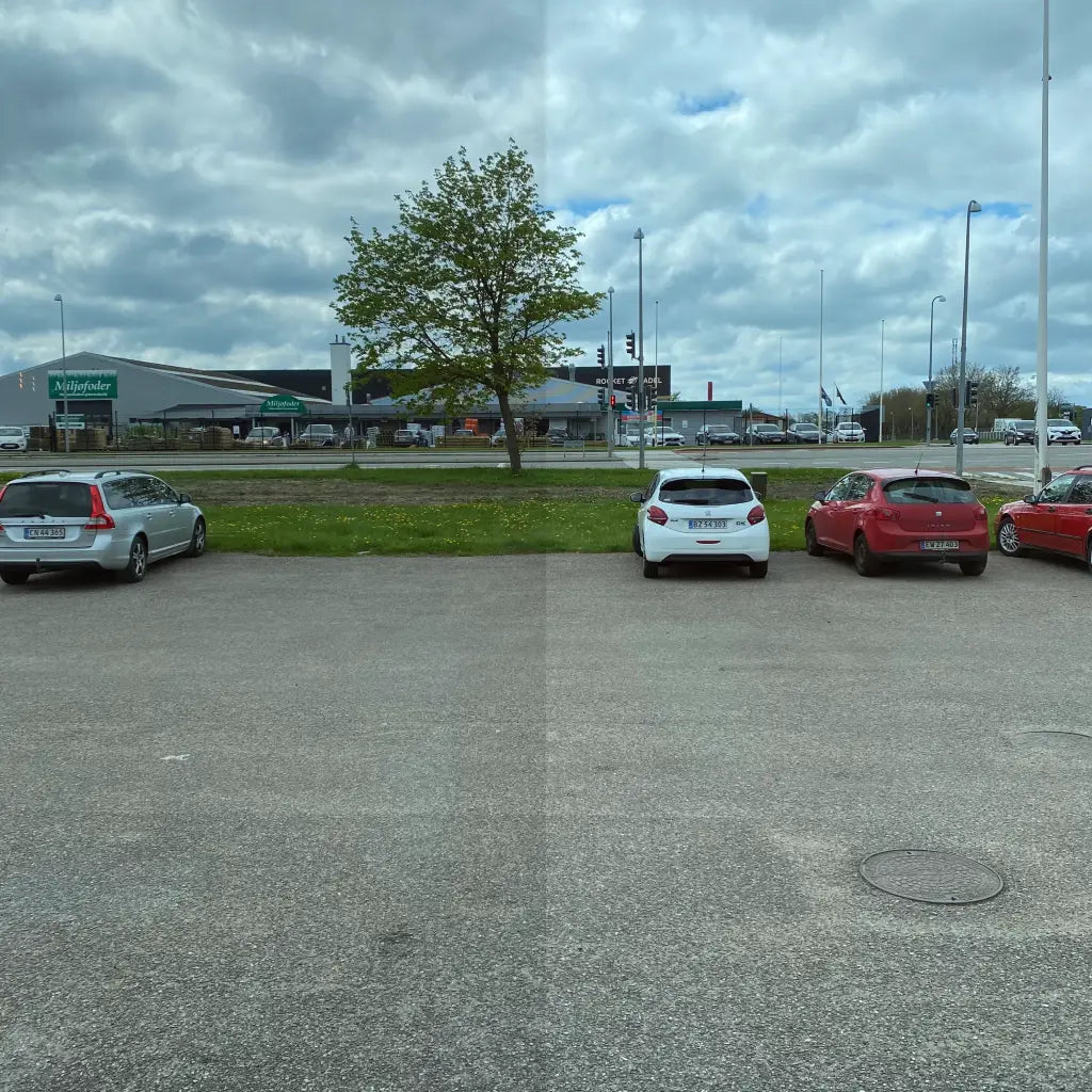 Parkeringsplads med biler; synlig linje deler toningsniveauer i vindue.