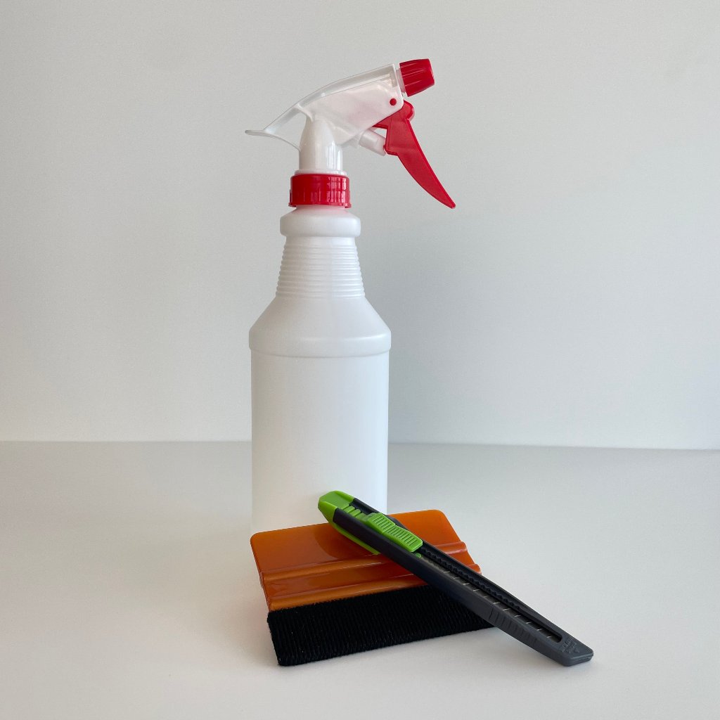 Hvid sprayflaske med rød aftrækker, orange skraber med filt og sort-grøn hobbykniv.