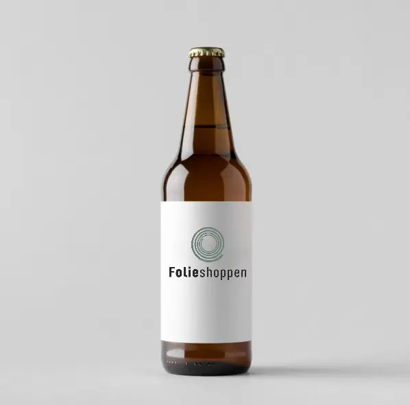Brun glasflaske med hvid etiket fra Folieshoppen, navnet står tydeligt. Flasken er forsejlet.