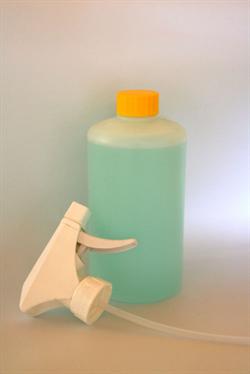 Gennemsigtig flaske med lyseblå væske, gul hætte og hvid spraydyse.