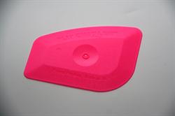 En lyserød skraber med afrundede kanter og en central cirkulær fordybning.
