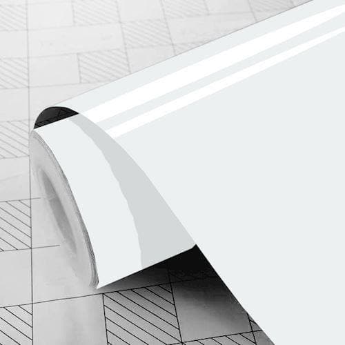 Glansfuld hvid folie i rulleformat på et gittermønstret underlag, delvist udrullet.