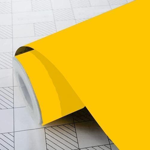 Gul klæbefolie i rulle på mønstret overflade, med glat tekstur.