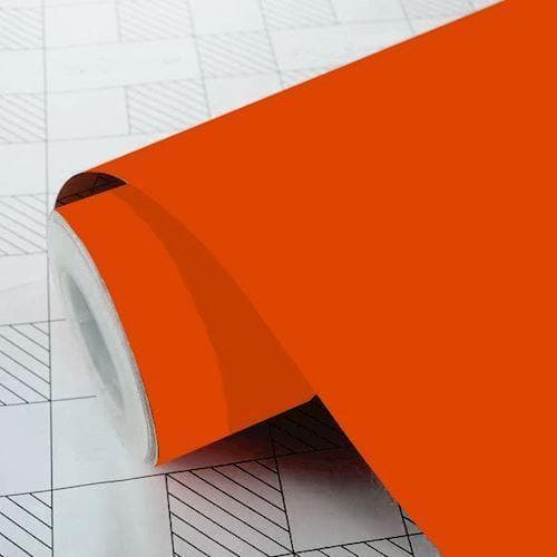 Orange vinylfolie i rulleform, delvist udrullet, viser solid farve og fleksibilitet.