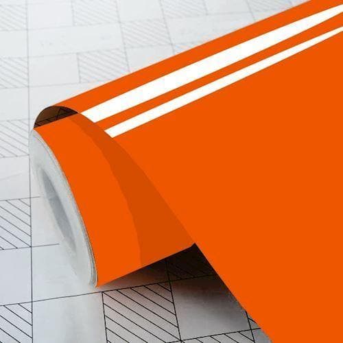 Rulle af blank orange vinylfolie, delvist udrullet på overflade med gittermønster.