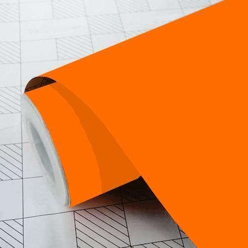 Rulle af pastel orange mat folie delvist udrullet på overflade med gittermønster.