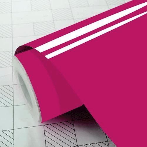 Blank, skinnende pink folie på rulle, delvist udrullet på overflade med gittermønster.