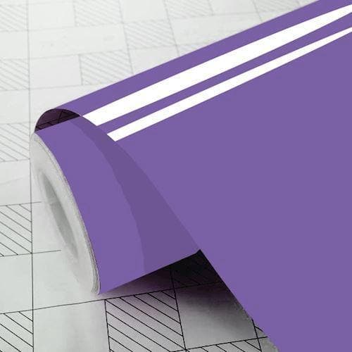 Rulle af lavendelfarvet selvklæbende vinylfolie, delvist udrullet på en overflade med gittermønster.