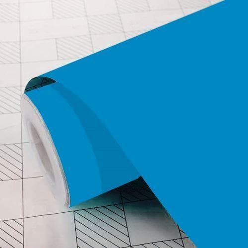 Rulle med lyseblå selvklæbende folie, delvist udrullet på overflade med måle- og skæremønster.