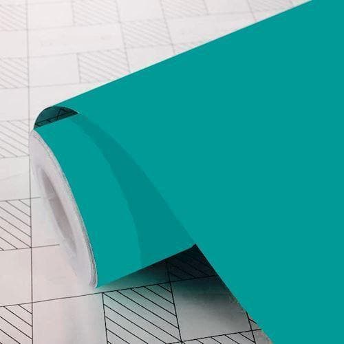 Rulle af mat turkis folie på mønstret overflade, delvist udrullet.