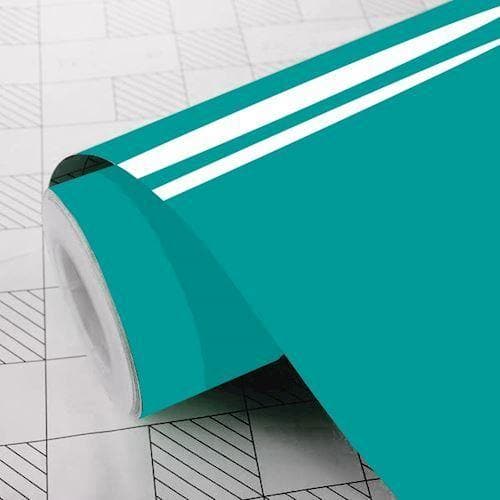 Rulle af turkis klæbefolie med glat overflade, delvist udrullet på mønstret underlag.