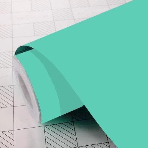 Rulle af mintgrøn mat folie delvist udrullet på en mønstret overflade.