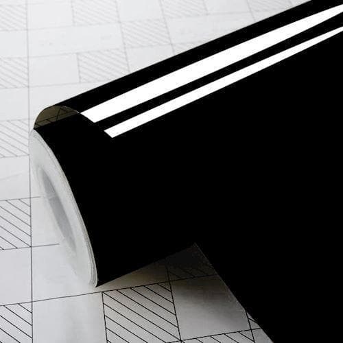 Blank sort folie i rulle med skinnende overflade på ternet baggrund, cylindrisk form.