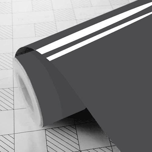 Rulle af mørkegrå folie, delvist udrullet, glat overflade, baggrund med gittermønster.