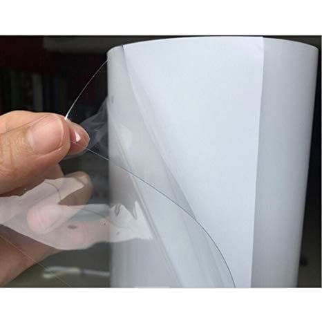 En person holder en blank, gennemsigtig folie væk fra dens bagpapir, som skinner i lyset.