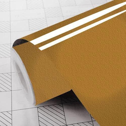 Rulle af blank, guld folie med reflekterende overflade, delvist udrullet på et gittermønster.