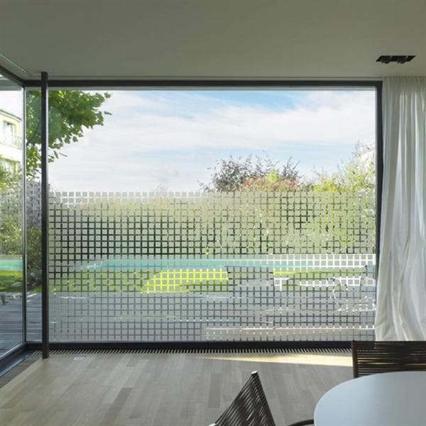 Stor glasrude med sandblæst film i geometrisk mønster, der giver lys og privatliv.