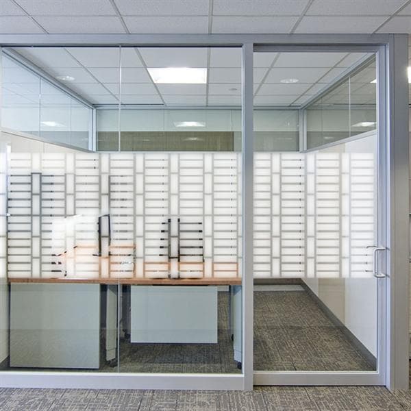 Sandblæst film med geometrisk mønster på glasvæg, giver privatliv i kontor med elegant design.