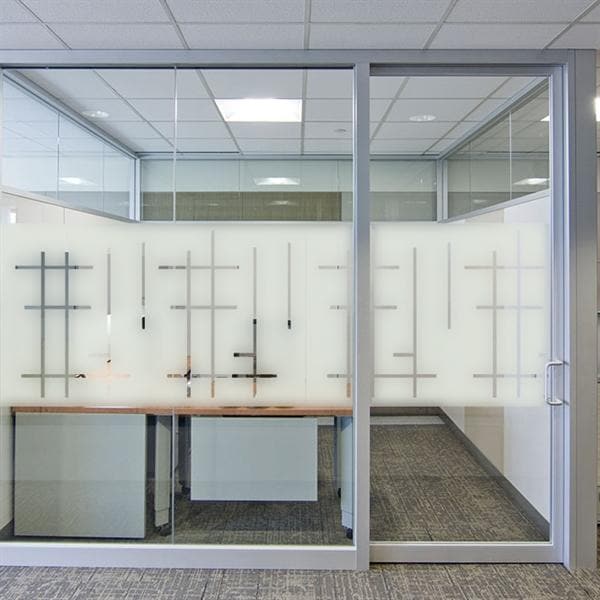 Frostet glasvæg med geometriske linjer i et kontor, giver privatliv og moderne udseende.