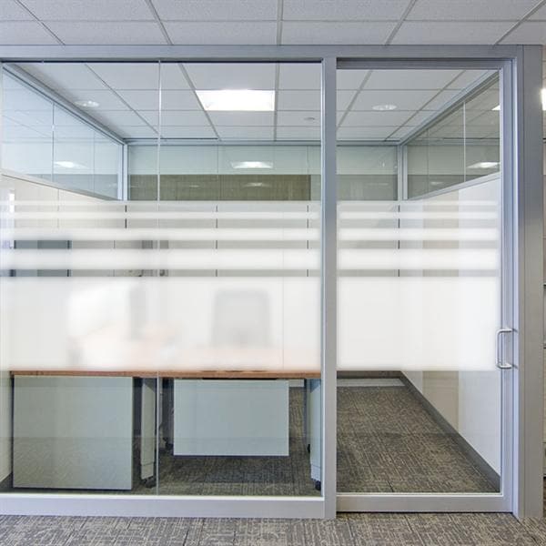 Glasvæg med sandblæst film, fra talje- til hovedhøjde, der giver privatliv og lysgennemgang.