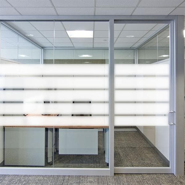 Glasvægge med vandrette froststriber i kontormiljø, giver privatliv og lysindfald.