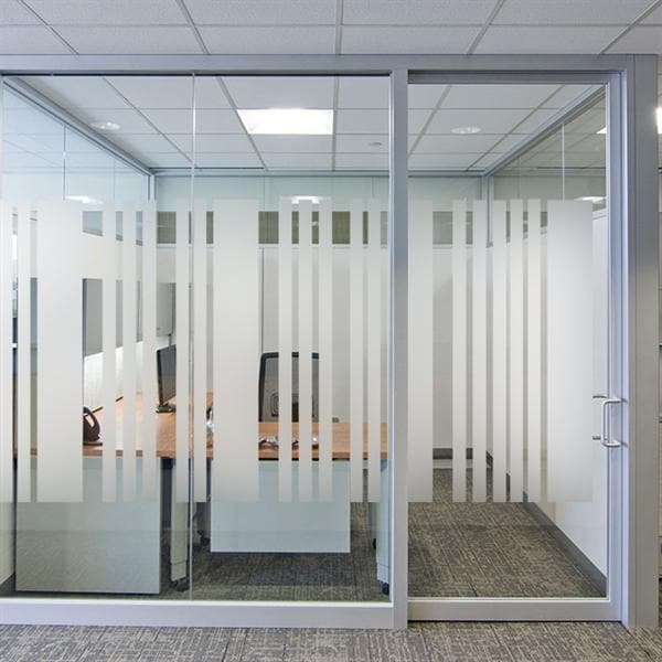 Moderne kontor med glasvæg, frostet design i striber, der balancerer privatliv og lysindfald.
