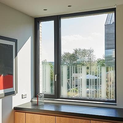 Sandblæst vinduesfilm med lodrette striber, der giver privatliv og slipper lys ind i et moderne rum.