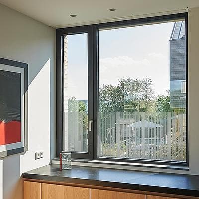 Vindue med mønstret film, der giver privatliv. Træskabe og maleri i moderne rum.