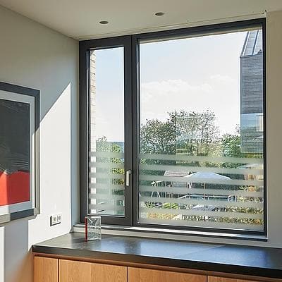 Vindue med sandblæst design og vandrette striber, der slipper lys ind og giver privatliv.