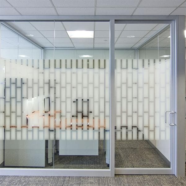 Kontor med glasvægge og sandblæst rektangelmønster, der giver privatliv og lader lys passere.