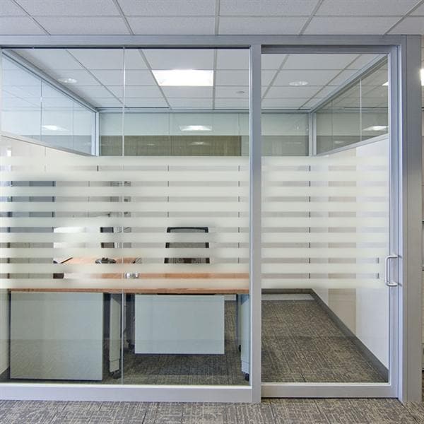 Glasvæg med horisontale frostede striber, giver lysgennemgang og privatliv på kontoret.