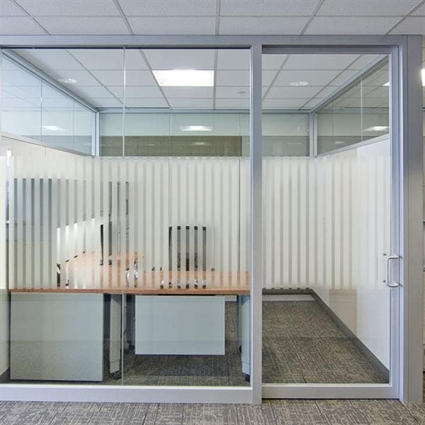 Kontor med glasvægge, frostet film i striber, indeholder skrivebord og stol.