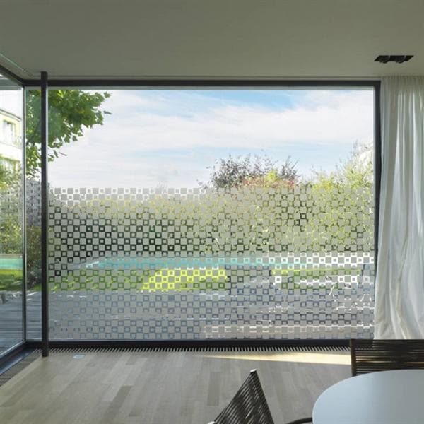 Stort glasvindue med mønstret sandblæst film, giver privatliv og lysindfald. Moderne æstetik.