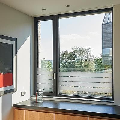 Vindue med sandblæst film i vandrette striber, semi-transparent, slipper lys ind, skjuler udsyn.