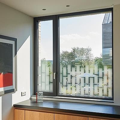 Vindue med designfolie af frostede rektangler på nederste halvdel, giver privatliv og stil.